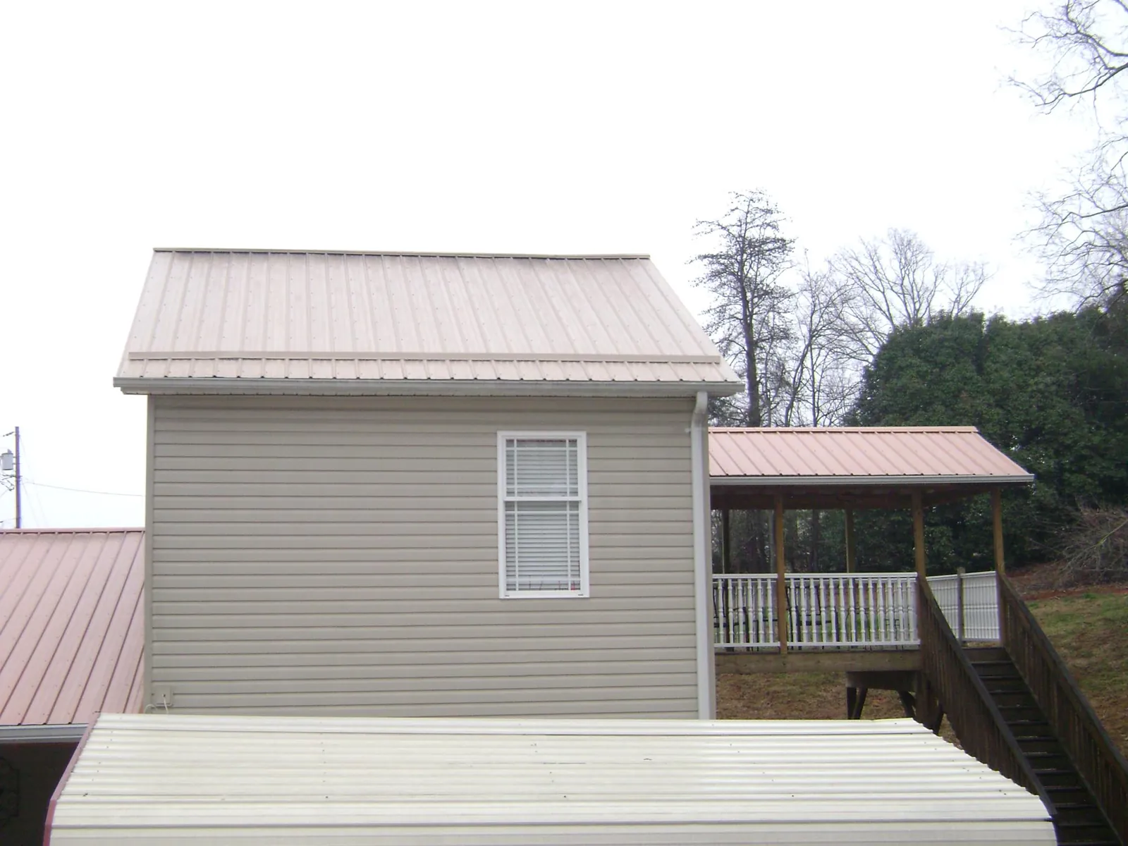 Tan metal roofs on a two story addition and attached porch, from a Roof Replacement job in Moscow